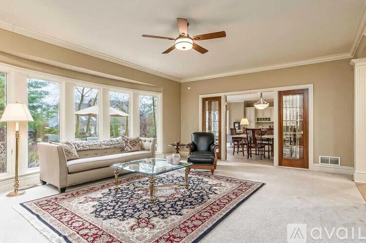 A living room with a rug, a chair, a couch, and a ceiling fan.