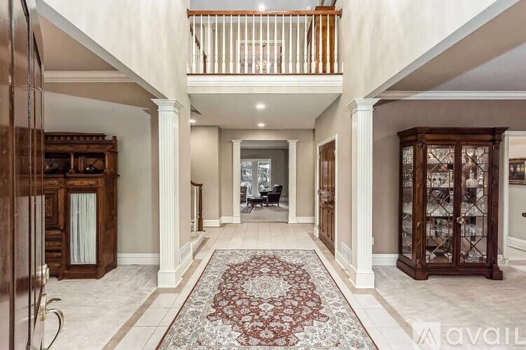 A large, elegant hallway with a patterned rug and a balcony with wooden railings.