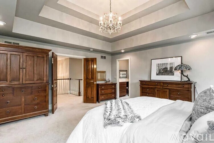 A bedroom with a large bed and a chandelier.