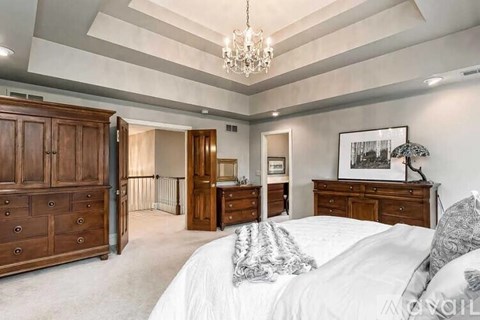 A bedroom with a large bed and a chandelier.