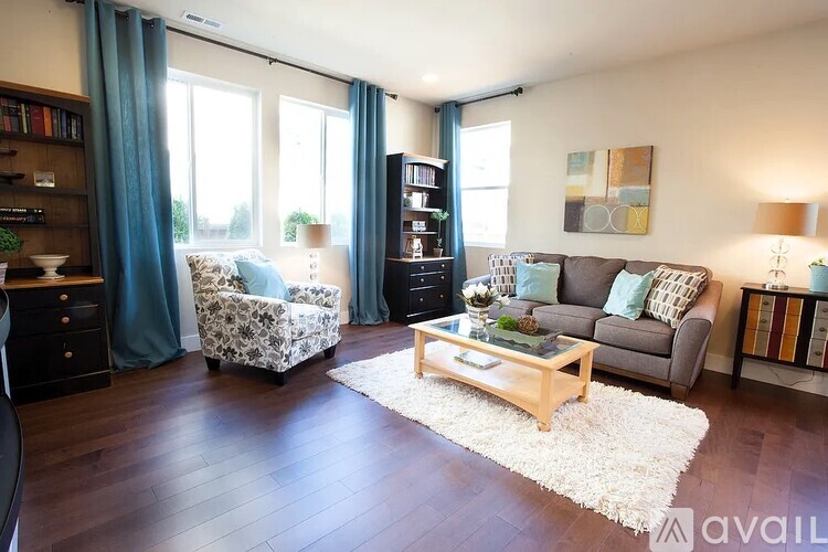 A living room with a grey couch, a coffee table, a chair, and a rug.
