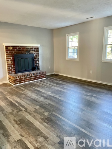 A room with a brick fireplace and wooden flooring.