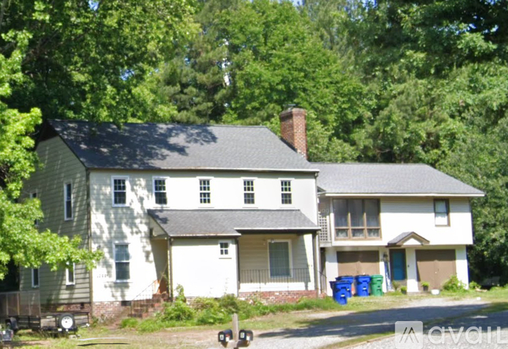 A two-story house with a garage is surrounded by trees.