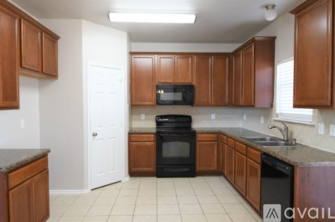 A kitchen with brown cabinets and black appliances.