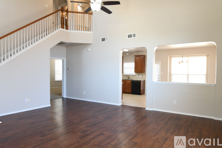 A spacious room with wooden floors and a staircase leading to the upper level.