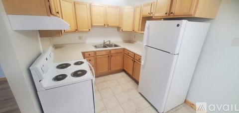 A kitchen with a white refrigerator and a white stove with four burners.