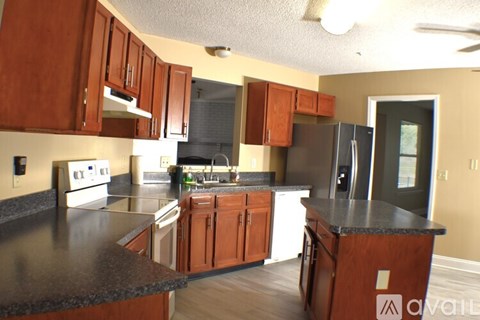 A kitchen with brown cabinets and a black counter top.
