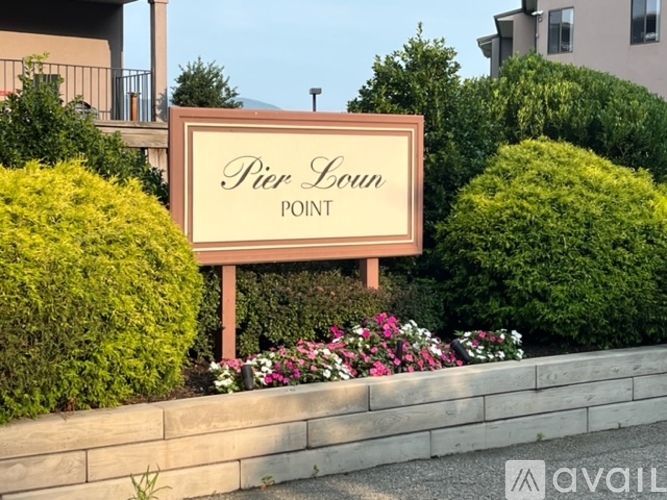 A sign that says "Pier Point" is surrounded by green bushes and flowers.