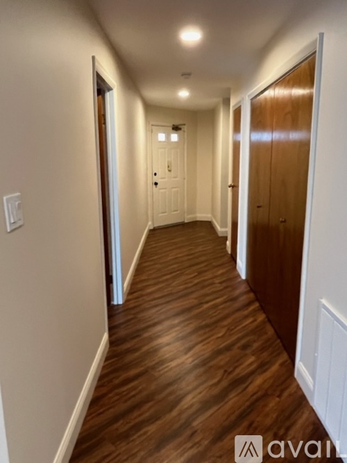A long hallway with wood floors and white walls.