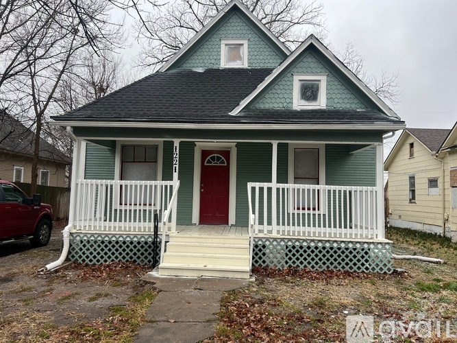 A small house with a red door and white porch.