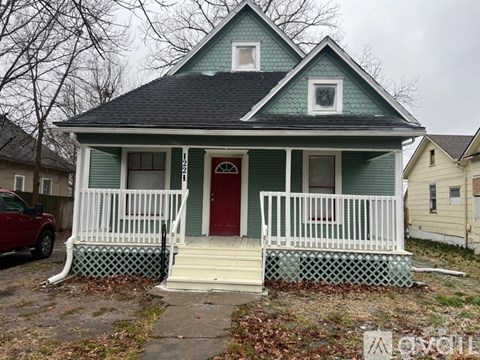A small house with a red door and white porch.