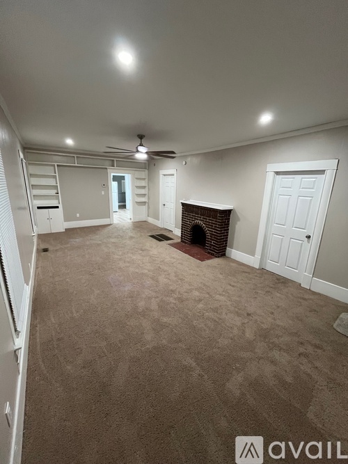 A living room with a fireplace and a carpeted floor.