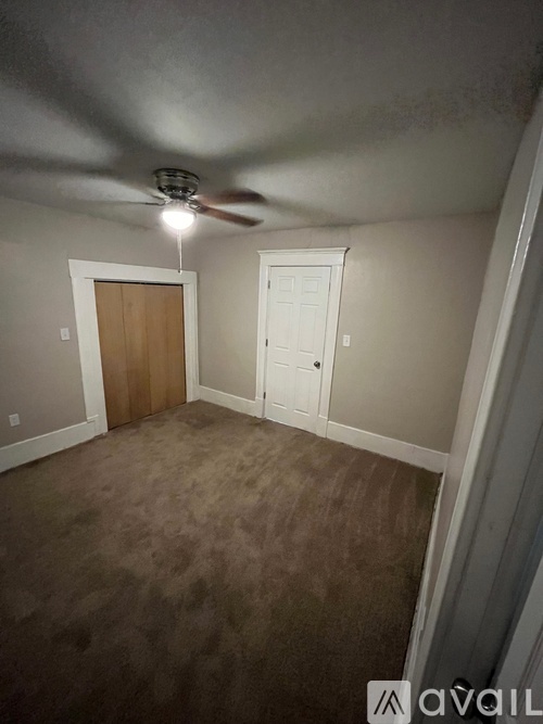 A room with a ceiling fan and carpeted floor.