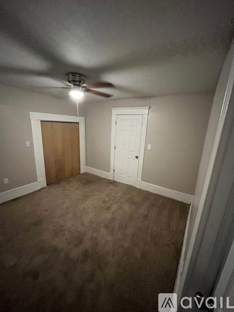 A room with a ceiling fan and carpeted floor.