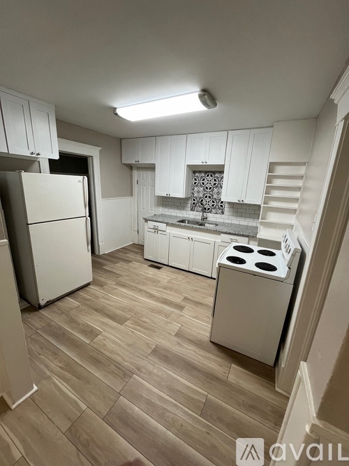 A kitchen with a refrigerator, stove, and cabinets.