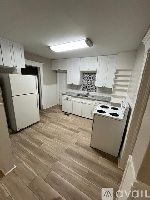 A kitchen with a refrigerator, stove, and cabinets.