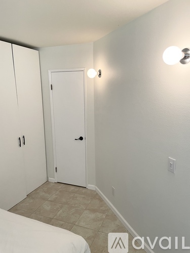 A small bedroom with a white bed and a white door.