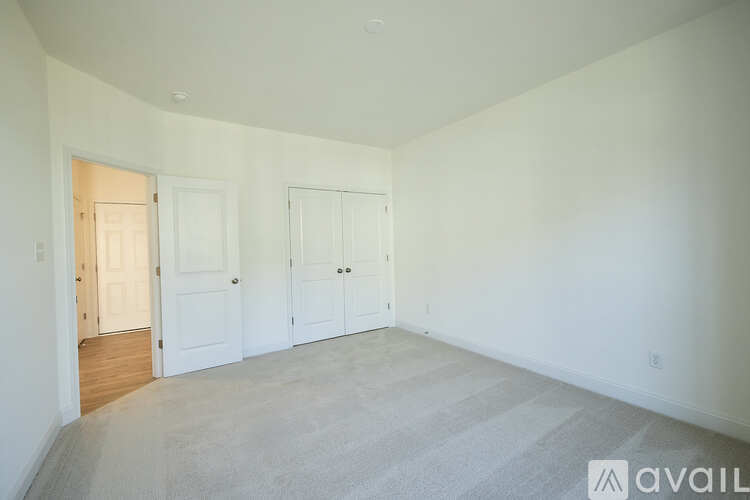 A room with a carpeted floor and two doors.
