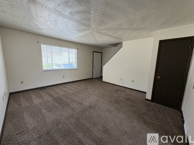 A room with a carpeted floor and a window with blinds.