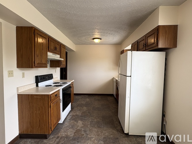 A kitchen with a white refrigerator and wooden cabinets.