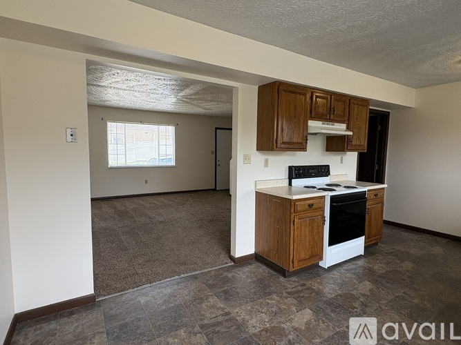 A kitchen with a white stove top oven and wooden cabinets.