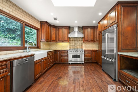 A kitchen with wooden cabinets and a stainless steel refrigerator.
