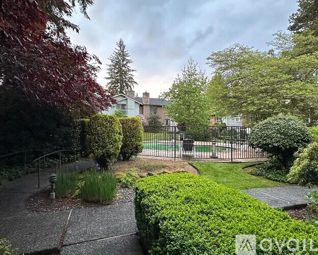 A garden with a fence and a house in the background.