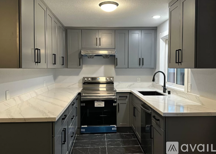 A kitchen with a marble countertop and dark cabinets.