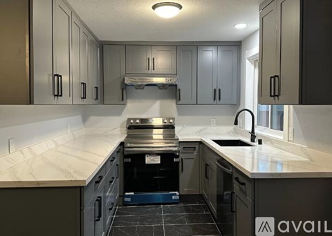 A kitchen with a marble countertop and dark cabinets.