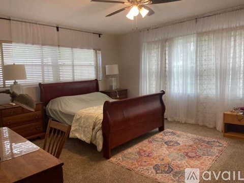 A bedroom with a bed, chair, and a rug.