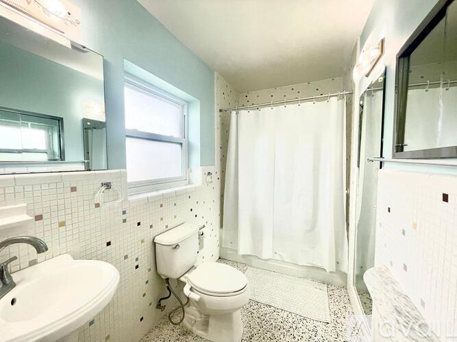 A white toilet sits in a bathroom with a white sink and a shower curtain.