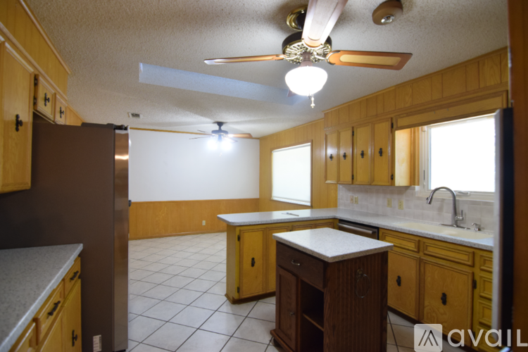 A kitchen with wooden cabinets and a ceiling fan.