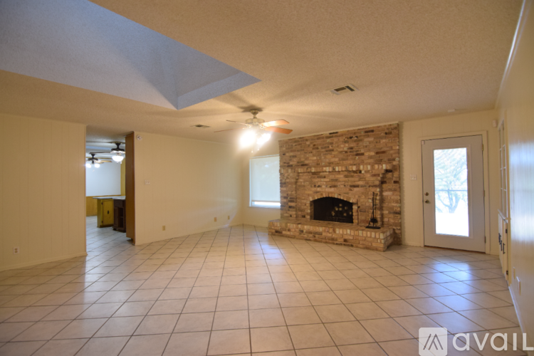 A living room with a stone fireplace and tiled flooring.