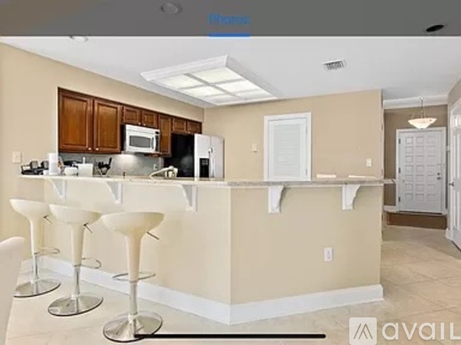 A kitchen with a bar area and white chairs.