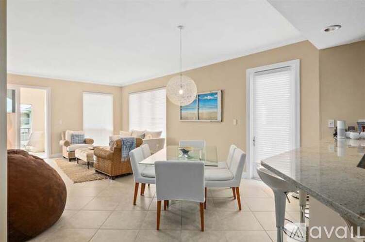 A modern dining room with a glass table and white chairs.