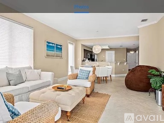 A living room with a white couch, a wicker chair, and a brown bean bag chair.