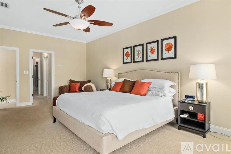 A bedroom with a large bed, a ceiling fan, and a nightstand with a lamp.