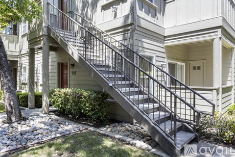 A staircase with a metal railing leads up to a door on a building.