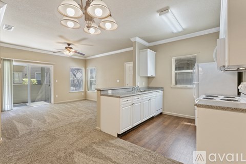 A kitchen with a refrigerator, stove, and a ceiling fan.