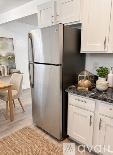 A stainless steel refrigerator stands in a kitchen with white cabinets.