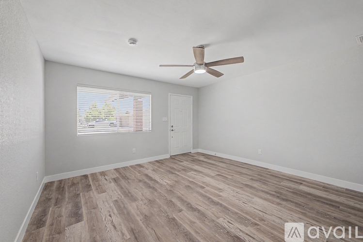 A room with a ceiling fan and wooden flooring.