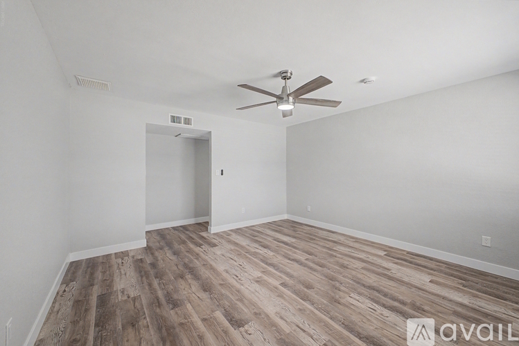 A room with a ceiling fan and wooden flooring.