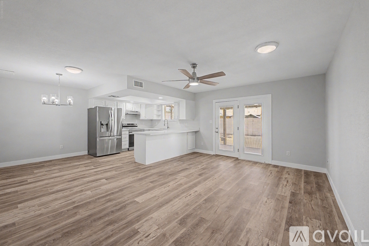 A spacious room with wooden flooring and a ceiling fan.