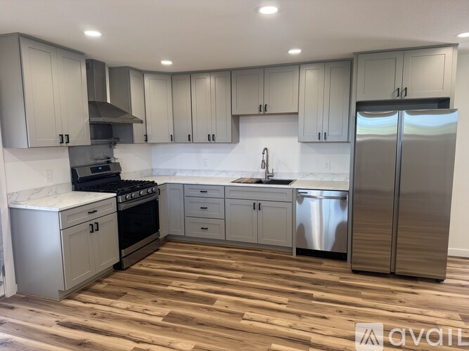 A modern kitchen with wooden floors and stainless steel appliances.