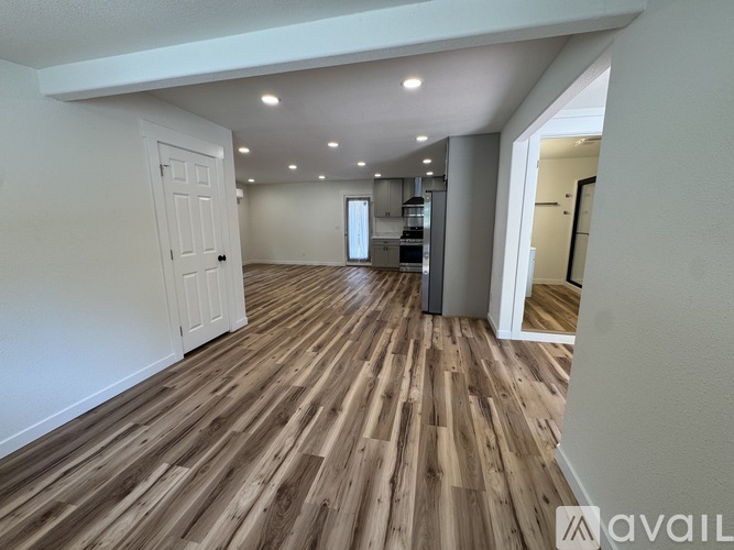 A spacious room with wooden flooring and white walls.