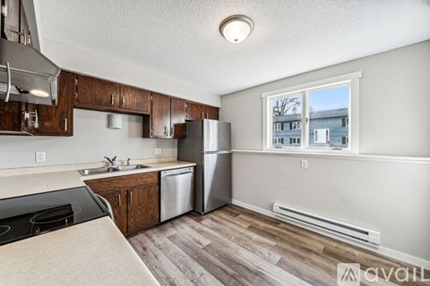 A kitchen with wooden cabinets and a stainless steel refrigerator.