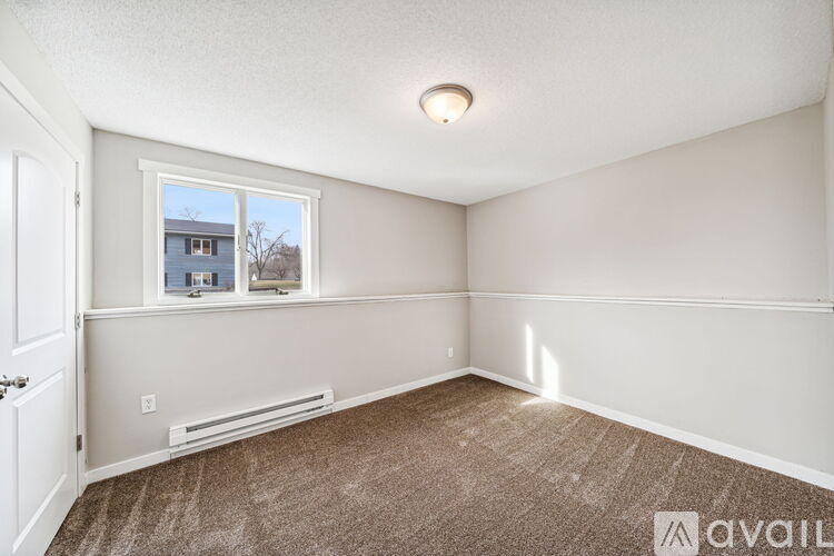 A room with a window and a carpeted floor.