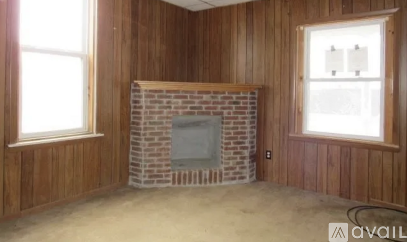 A room with wooden walls and a brick fireplace.