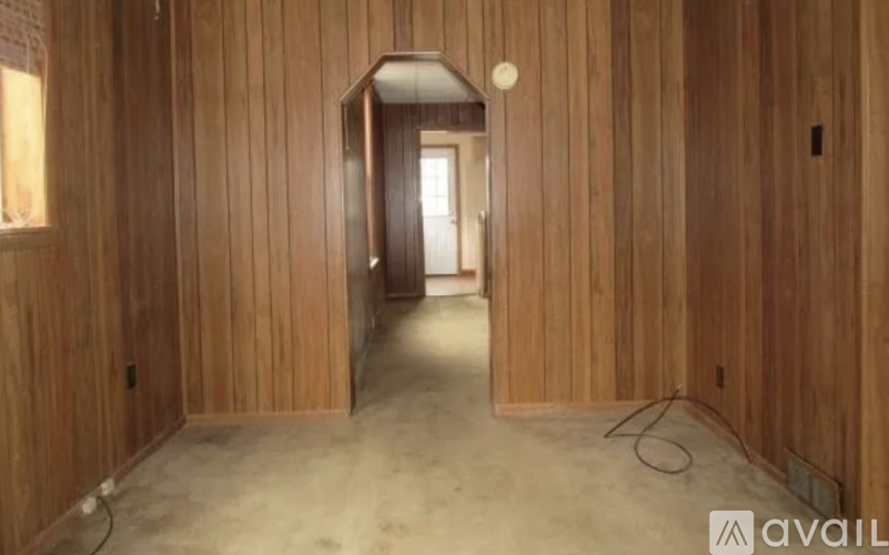 A room with wooden walls and a doorway leading to another room.
