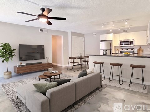 A living room with a grey couch and a television on a wooden stand.